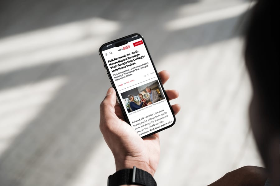 A hand holding a phone showing a USA News article.